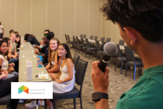 Student speaking into a mic in front of a group of other students.