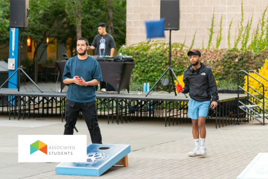 Students playing cornhole in Seawolf Plaza with a DJ in the background.