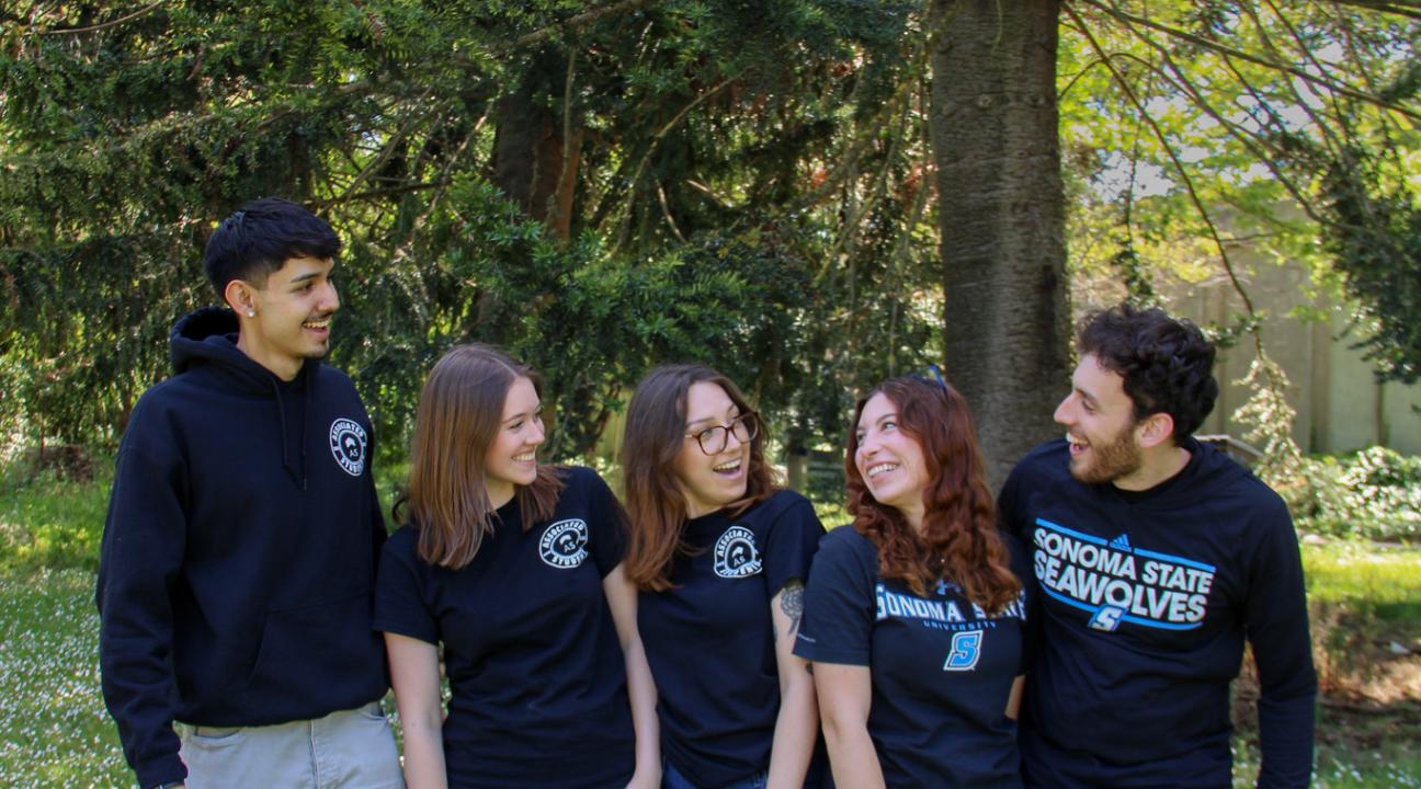 Five student staff members smiling at each other wearing AS sweatshirts