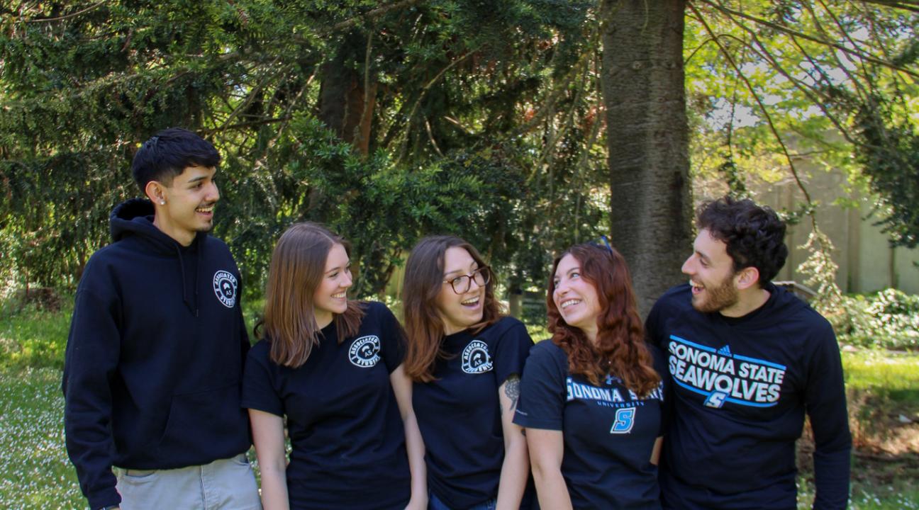 Five student staff members smiling at each other wearing AS sweatshirts