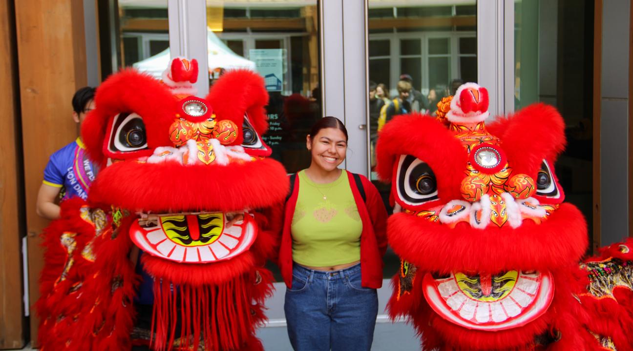 Student posing with two lion dancers.
