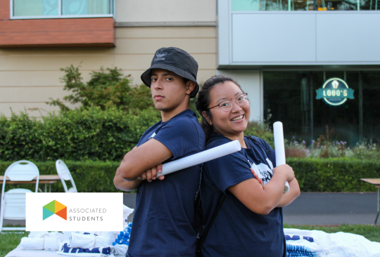 Two students posing back to back holding glow sticks.