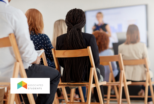 A room of people sitting watching a presentation.