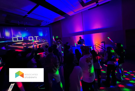 Students dancing with LED lights with a DJ playing music.