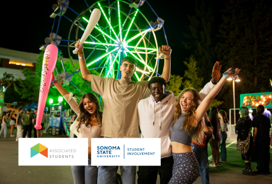 Four students posing with a ferris wheel in the background.