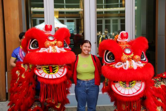 Student posing with two lion dancers.