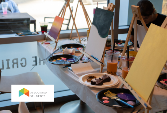Canvases on easels set up on a table. Plates with brownies on the table.