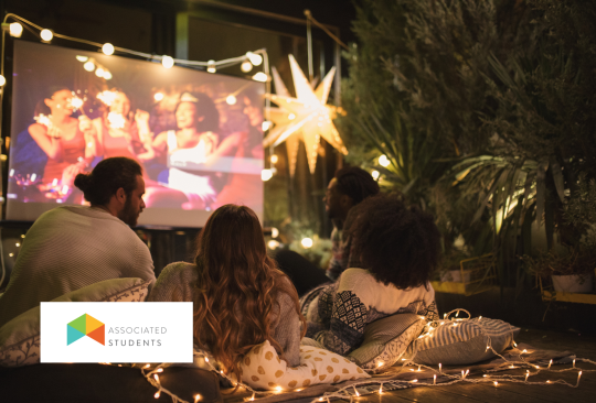 group of young adults watching a film set up on an outdoor projector display.