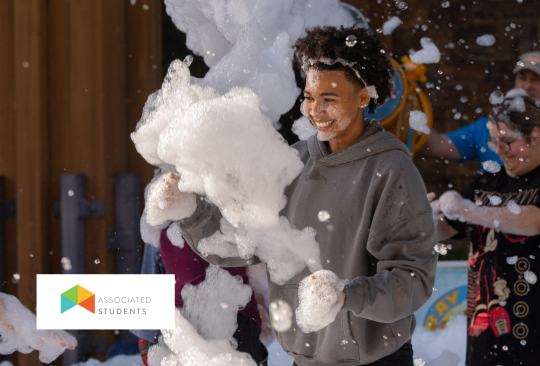 Student smiling surrounded by foam bubbles in Seawolf Plaza